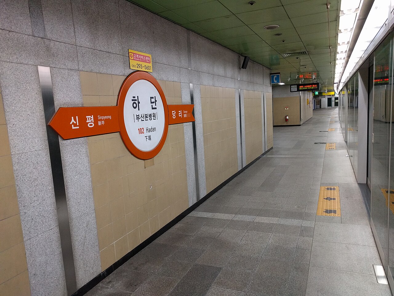 Empty underground subway platform with an orange round Hadan station sign on the wall and glass screen doors on the right