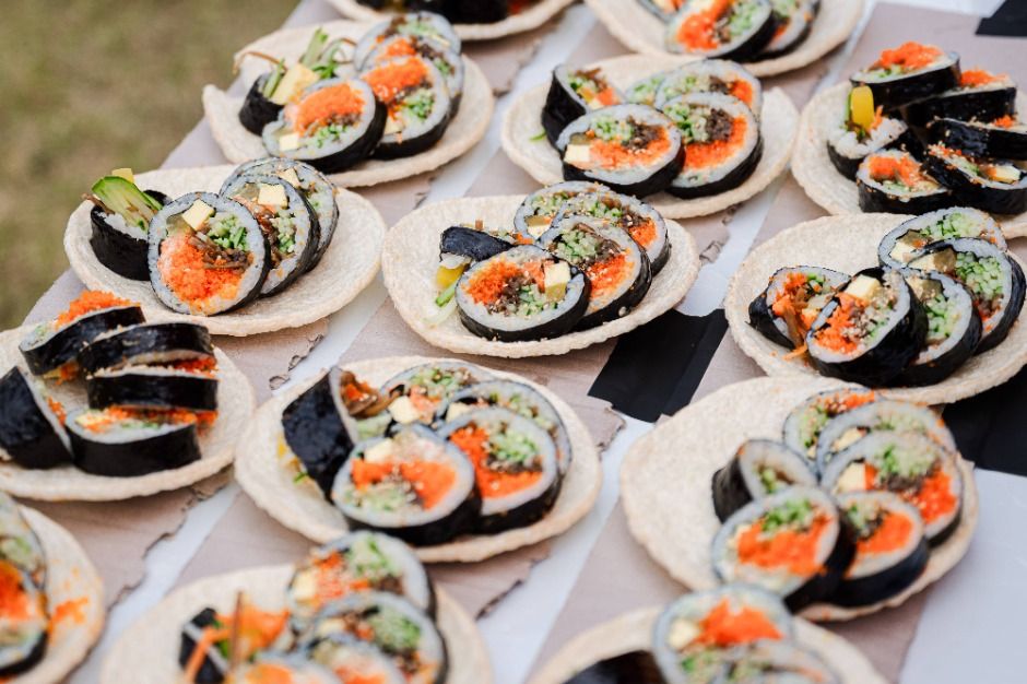 Rows of round plates holding sliced gimbap rolls with carrot, cucumber and other fillings on a festival table