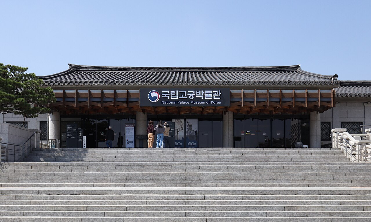 Hanok-style roof over the National Palace Museum of Korea entrance, with its bilingual sign above wide granite steps