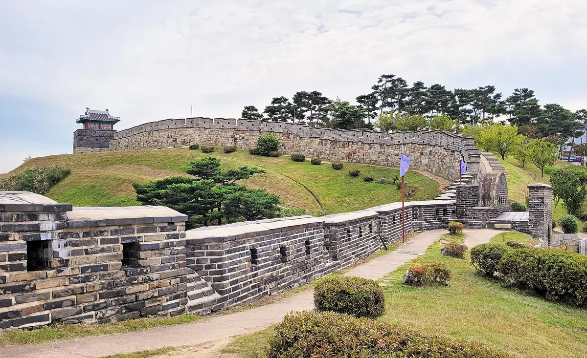 Stone ramparts and watchtower of Hwaseong Fortress in Suwon under a blue sky